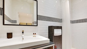 Een moderne badkamer met een witte wastafel, een grote spiegel en een douchehoek.