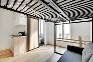 Eine moderne Wohnung mit Küchenzeile, einer Schiebetür zum Badezimmer, einem Balkon mit Ausblick und einer Couch.