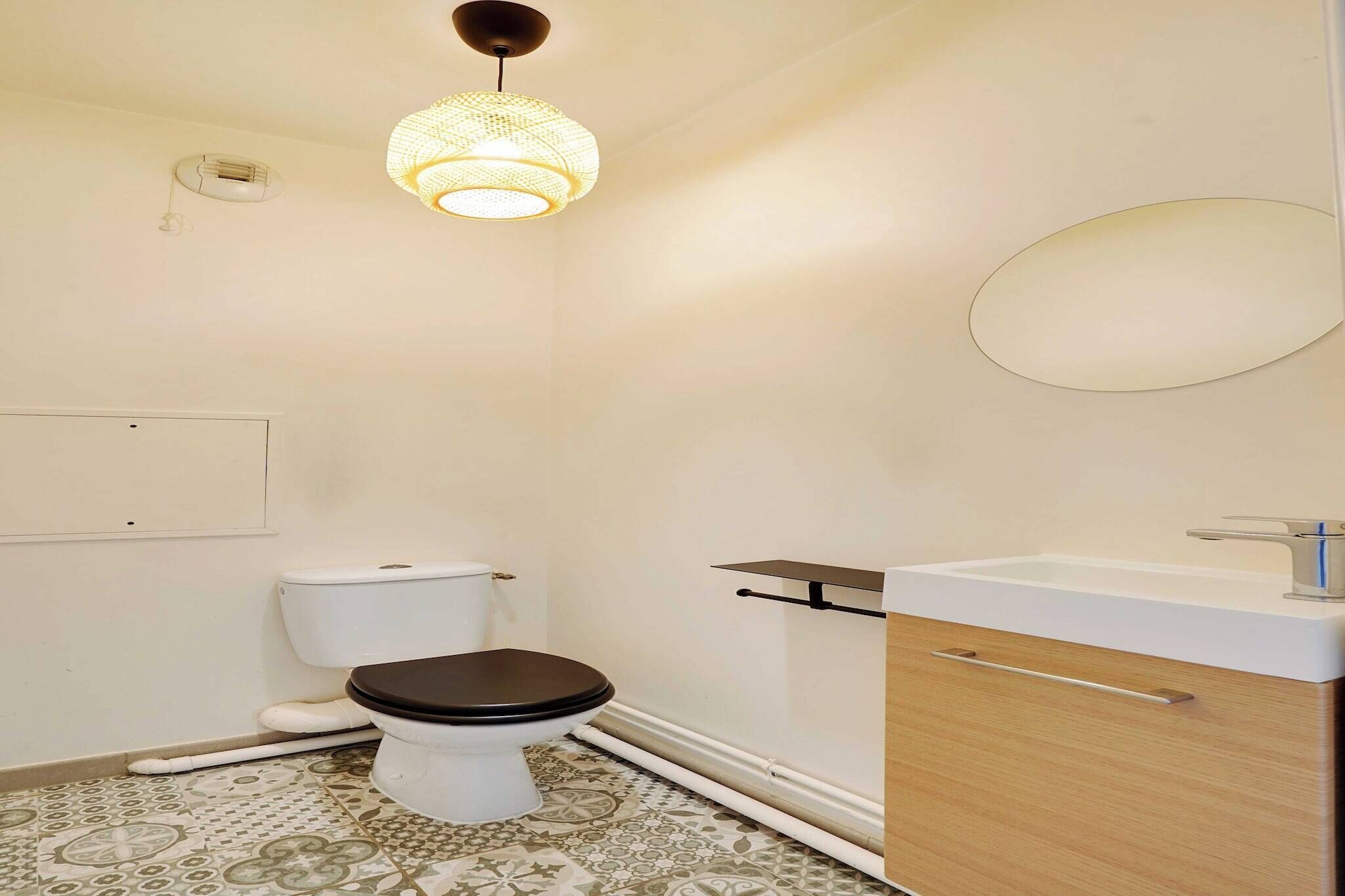 A small, clean bathroom with a toilet, sink, and a hanging light fixture.