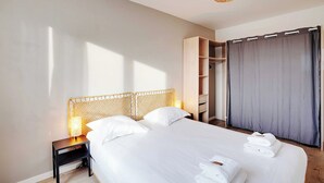 Ein Hotelzimmer mit einem großen Bett, einem Nachttisch mit Lampe, einem Kleiderschrank und einem grauen Vorhang.