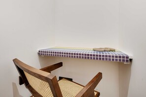 A cozy space with a shelf featuring a checkered tile pattern and a wooden chair with a woven seat.