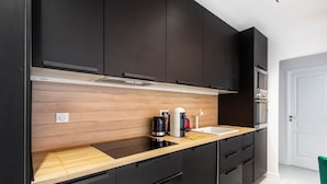 A modern kitchen with dark cabinets, a wooden countertop, a built-in oven, and a coffee maker. - Magnificent apartment - 1BR/4P - Picpus (Paris)