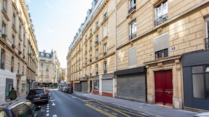 A street lined with historic buildings, parked cars, and closed shop shutters. - Magnificent apartment - 1BR/4P - Picpus (Paris)