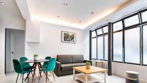 A modern living room with a grey sofa, teal chairs, a wooden coffee table, and a large window with black frames. - Magnificent apartment - 1BR/4P - Picpus (Paris)