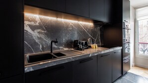 Eine moderne Küche mit dunklen Schränken, einer Marmor-Spritzschutzwand und einem Einbauofen.