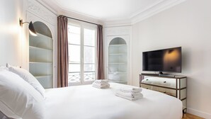 Ein Hotelzimmer mit einem großen Bett, einem Fernseher und einem Schrank mit Glastüren.
