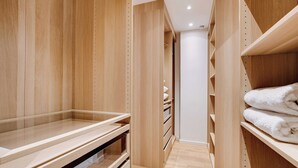 A wooden walk-in closet with open shelves and drawers, a hanging rod, and a folded towel on the right. - Passy / Eiffel Tower - Amazing 2BR with garden (Paris)