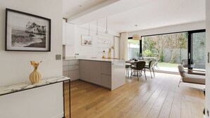A modern kitchen with a marble countertop, a dining area with a table and chairs, and a large window overlooking a garden. - Passy / Eiffel Tower - Amazing 2BR with garden (Paris)