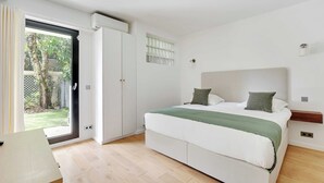 A bedroom with a bed, a sliding glass door to a garden, and a small window. - Passy / Eiffel Tower - Amazing 2BR with garden (Paris)