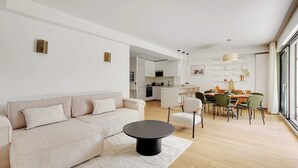 A modern living room with a sofa, a round coffee table, and a dining area with chairs and a table. - Passy / Eiffel Tower - Amazing 2BR with garden (Paris)