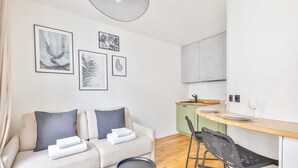 Un soggiorno moderno con un divano, un'area pranzo con un tavolo e sedie in legno e una cucina con un armadietto verde.