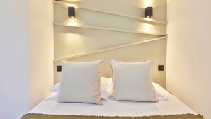 Camera d'albergo con un letto, due cuscini e una lampada fissata al muro.