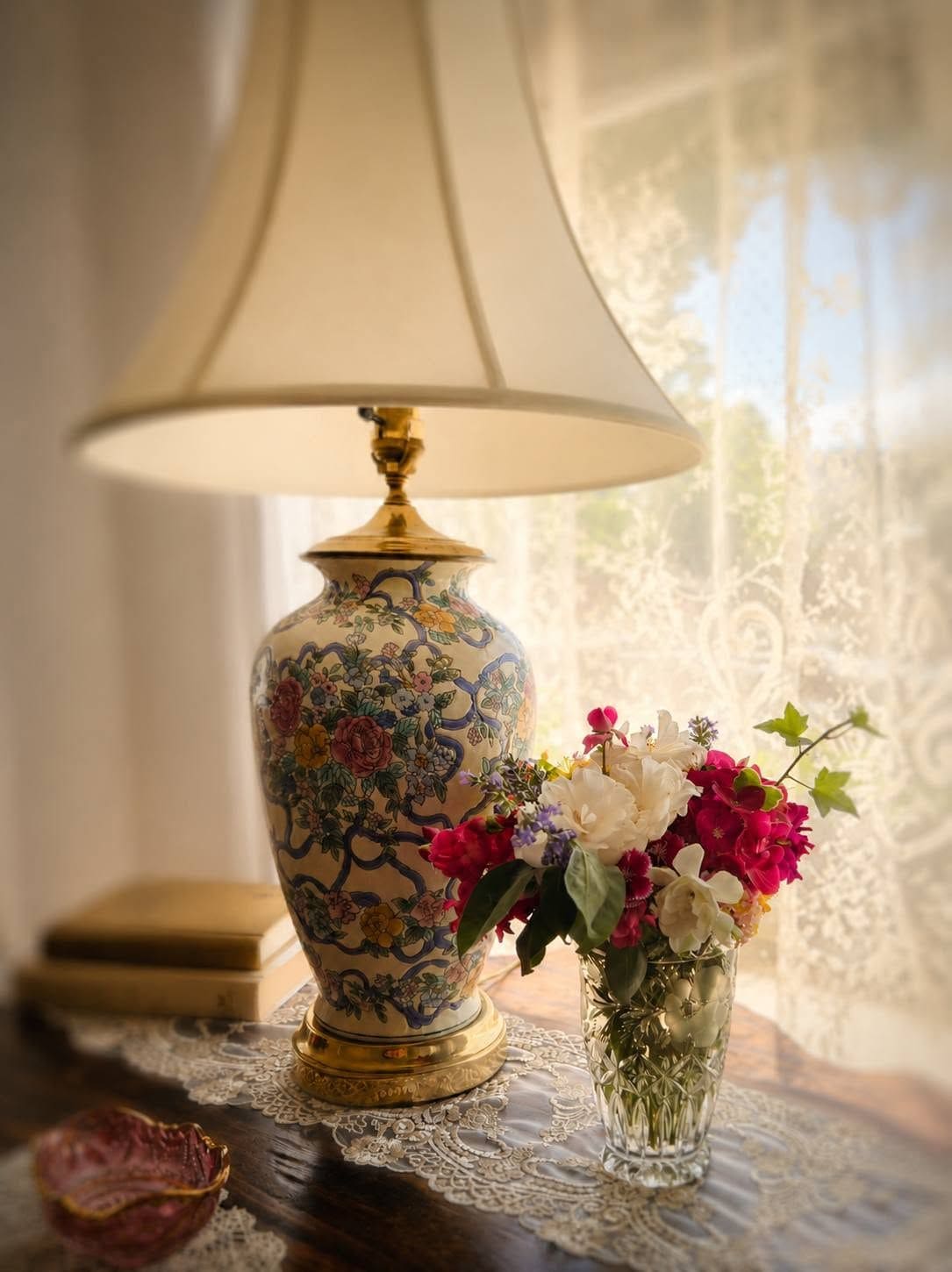 A table with a decorative lamp, a vase with flowers, and a book.