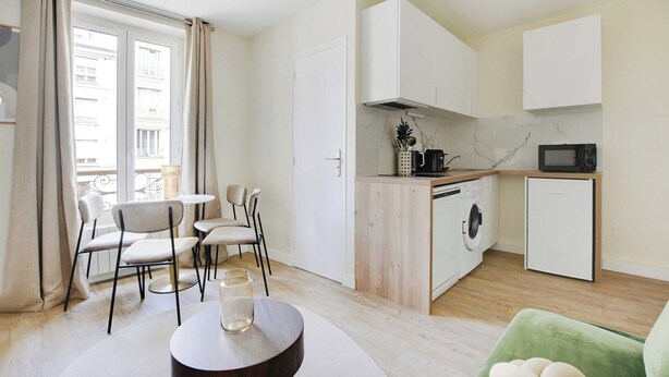 Une cuisine moderne équipée d’un lave-linge, d’un four à micro-ondes et d’un réfrigérateur compact.