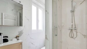 Une salle de bain moderne avec un pare-baignoire en marbre, une douche en verre et des toilettes.
