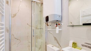 A modern bathroom with a glass-enclosed shower, a toilet, and a sink with toiletries. - Cosy apartment -1BDR/3P - Ivry-sur-Seine (Ivry-sur-Seine)