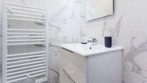 A bathroom with a white marble sink, a white towel rack, and a mirror above the sink.