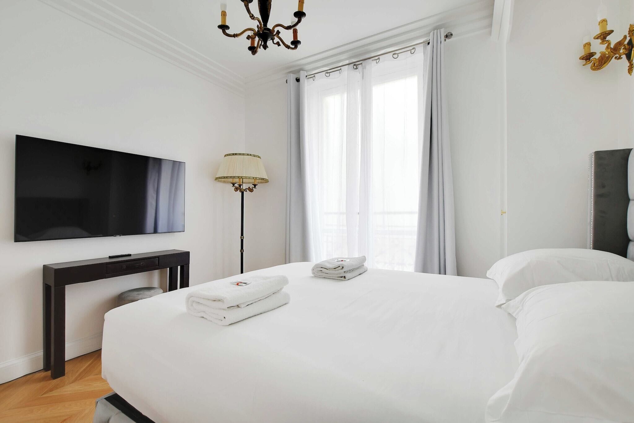 Une chambre d’hôtel avec un grand lit, un téléviseur à écran plat, un bureau et une lampe.