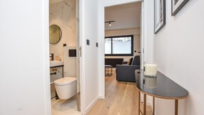 Een modern appartement met een marmeren badkamer, een eethoek en een woonkamer met een bank en een tafel.
