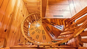 Una escalera espiral de madera en una cabaña con paredes de madera.