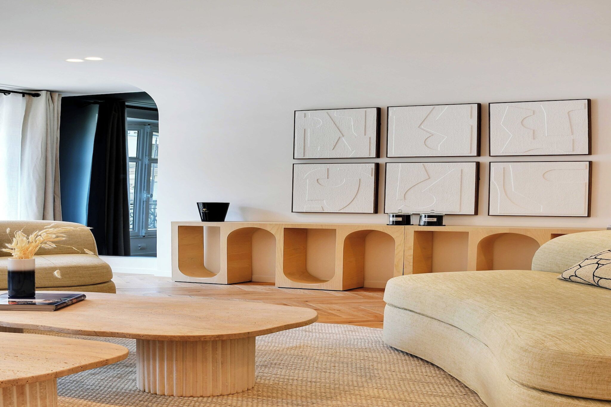 Een moderne woonkamer met een bank, salontafel en een console met decoratieve objecten.