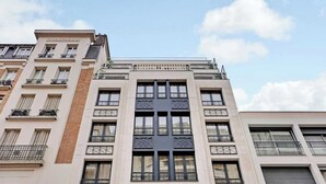 Un edificio de varios pisos con una entrada central y balcones.