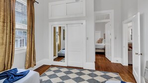 Une chambre à coucher avec un lit, un miroir et une porte donnant sur une autre pièce.