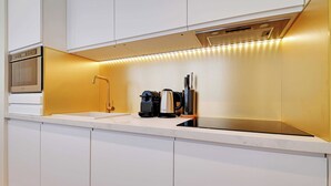 A modern kitchen with white cabinetry, a built-in oven, a sink, and a coffee maker.