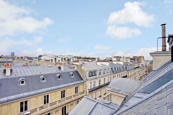 A view of a cityscape with multiple buildings, including a prominent building with a large dome and a chimney.
