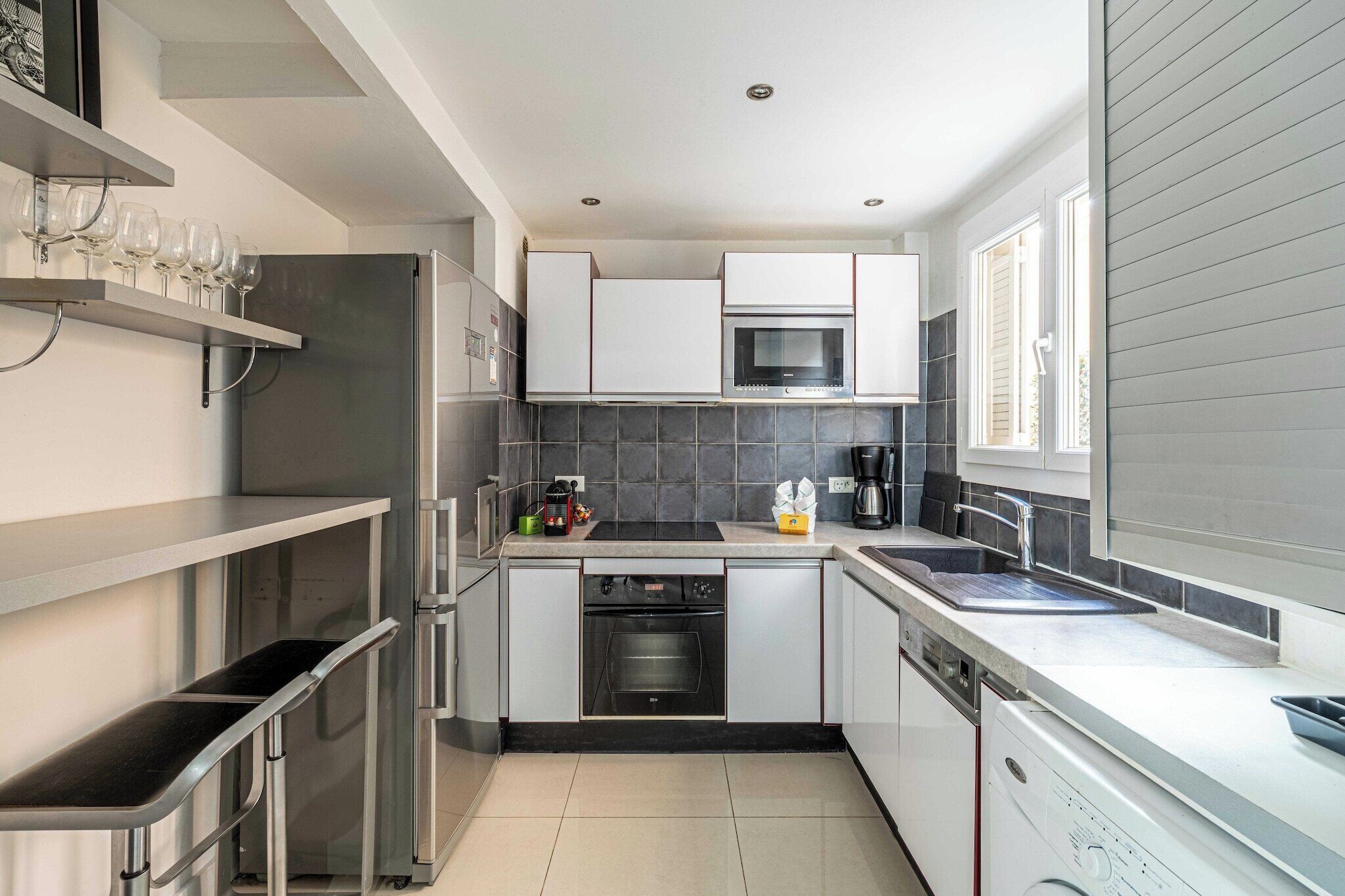 A modern kitchen with stainless steel appliances, white cabinetry, and a dishwasher.