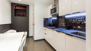 Una cocina moderna con armarios blancos, encimera negra, microondas y cafetera.