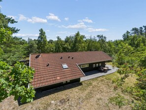 A single-story house with a tiled roof, a deck, and a small window.