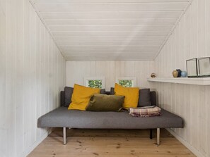 A room with a grey sofa, two windows, a wooden floor, and a white wall.
