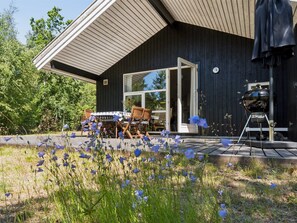 A modern house with a covered patio, a barbecue grill, and a garden with wildflowers. - "Aimo" - 300m from the sea by Interhome (Nexø)