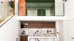 A modern kitchen with a marble countertop, wooden cabinets, and a glass railing above.
