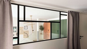 A room with a large window, a bed, and a door.
