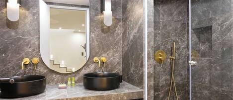 A bathroom with two black sinks, a mirror, and a gold showerhead.