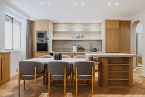 A modern kitchen with built-in appliances, a dining area with a table and chairs, and wooden cabinetry.