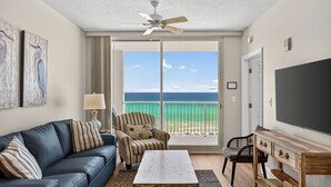 Une chambre avec un balcon, un ventilateur de plafond, une télévision, un canapé, une chaise et une table.