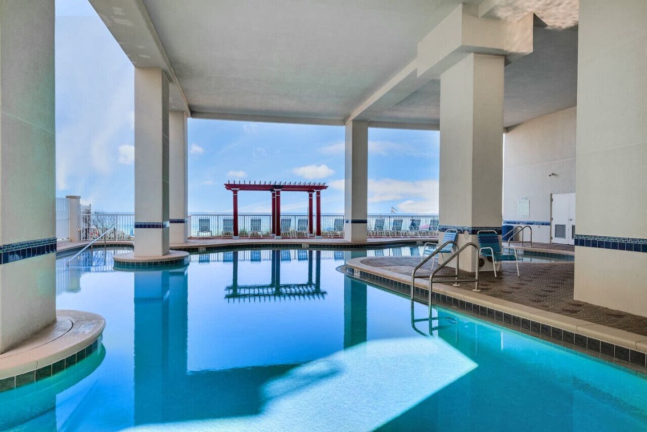 An indoor swimming pool with clear blue water, a red gazebo, and a view of the city skyline.
