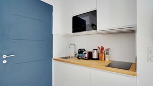 Eine kleine Küche mit weißen Schränken, einer blauen Tür, einer Mikrowelle, einem Toaster und einem Spülbecken.