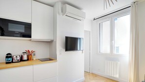 Eine moderne Küche mit weißen Schränken, einer eingebauten Mikrowelle und einem Flachbildfernseher.