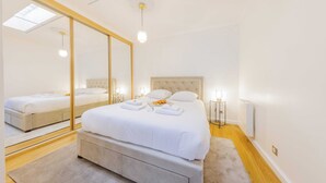Una camera da letto moderna con un letto grande, uno specchio, lampade da comodino e un lucernario.