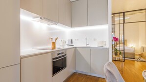 Una cucina moderna con mobili bianchi, forno integrato e pavimento in legno.