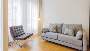 Un soggiorno moderno con un divano grigio, una poltrona in pelle marrone e cuscini decorati.