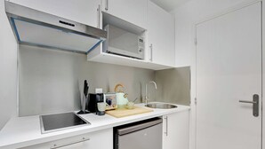 Eine kompakte Küche mit weißen Schränken, einer Mikrowelle, einem Toaster, einem Spülbecken und einem Geschirrspüler.