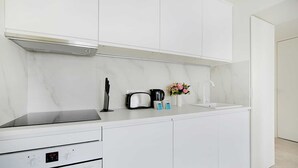 A modern kitchen with white cabinetry, a built-in oven, and a stainless steel range hood.