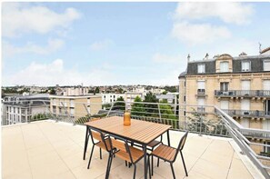 Enjoy an outdoor space with a table and chairs, taking in the views of the surrounding urban landscape.