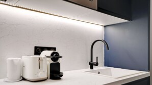 A modern kitchen with a white countertop, a built-in sink, a black faucet, and a coffee maker.