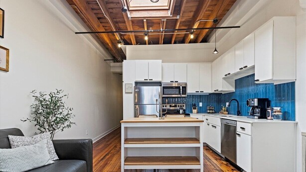 A modern kitchen with white cabinets, a wooden ceiling, and a skylight. - Oak St. Loft #2 - Walk to T-Mobile, P&L, Streetcar (Kansas City)